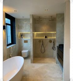 a bathroom with a tub, toilet and shower in it's center wall is illuminated by recessed lighting