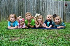 five children laying in the grass with their hands on their hipss and mouths open