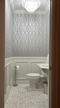 a white toilet sitting in a bathroom next to a sink under a chandelier