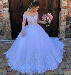 a woman in a blue wedding dress holding flowers and looking down at the ground with her hand on her hip