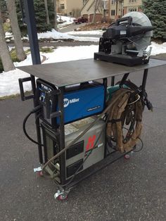 an outdoor work station with equipment on it in the middle of a driveway next to snow covered trees