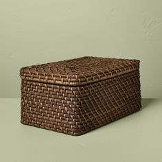 a brown wicker box sitting on top of a green table next to a wall