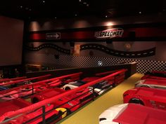 a row of red and white cars parked in front of a wall with the words speedway on it