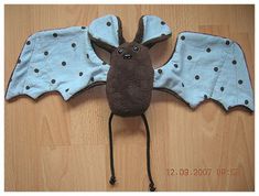 a stuffed animal bat with polka dots on it's wings and feet, sitting on a wooden floor