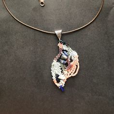 a beaded necklace is displayed on a black surface with a gold chain and two pendants