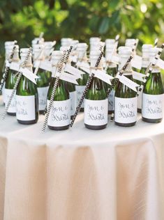 there are many small bottles on the table with paper straws in them and place cards attached to each bottle