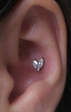 a woman's ear is shown with a single diamond in the shape of a heart