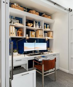 a home office with white shelving and blue walls