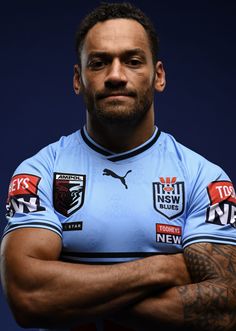 a man in a blue jersey is posing with his arms crossed and looking at the camera