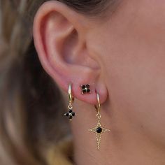 a woman wearing gold earrings with black stones