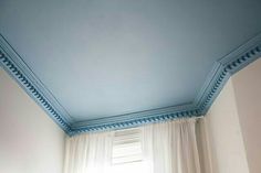 the ceiling is painted blue and has white curtains on it, along with a window