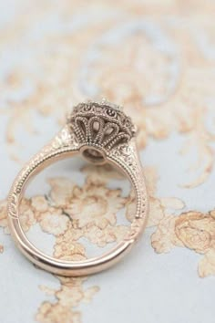 an antique style diamond ring sitting on top of a table