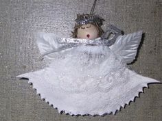 an angel ornament hanging from a string on a gray cloth covered tablecloth