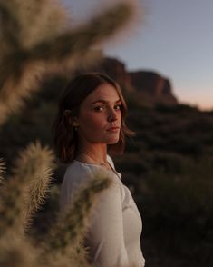 a woman is standing in the desert with her hand on her hip and looking off into the distance