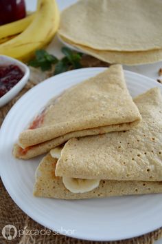 three quesadillas on a white plate next to some fruit