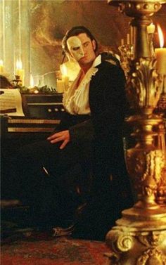 a man sitting in front of a piano wearing a mask