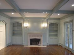 an empty living room with fireplace and built in bookcases