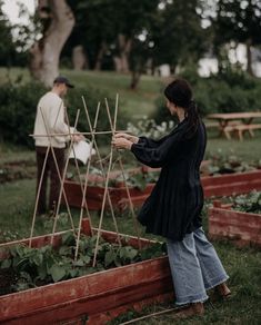 a woman standing next to a wooden garden planter