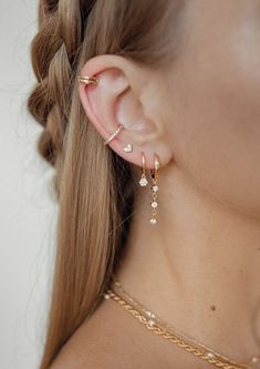 a close up of a woman's ear wearing gold jewelry