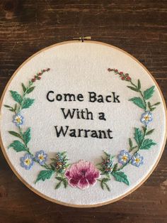 a hand embroidered sign that says, come back with a warrant on the inside of it