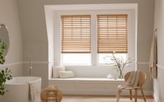 a white bathroom with wooden blinds and a window seat