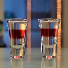 two shot glasses filled with liquid sitting on top of a table