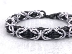 a black and silver bracelet on a white surface