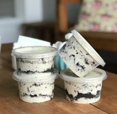 four plastic containers filled with ice cream sitting on top of a wooden table