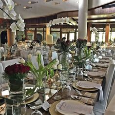 the tables are set with place settings and flowers in vases on each side of the table