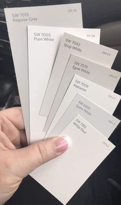 a person holding five different white paint samples