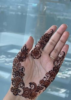 a hand with henna tattoos on it is holding something in the air and looking out