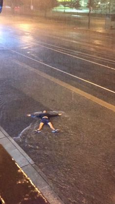 a person standing in the middle of a street with their arms spread out and feet on the ground