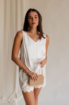 Introducing our Monroe Off White Satin Tank Top, a luxurious essential that epitomizes elegance and versatility. Crafted from sumptuously soft satin fabric in a timeless off-white hue, this tank top exudes sophistication with every wear. The graceful v-neckline adds a touch of allure, framing your décolletage with understated charm. Whether dressed up with statement jewelry for a night out or paired with casual denim for a relaxed daytime look, the Monroe Tank effortlessly transitions from day t Elegant V-neck Tank Top For Vacation, Chic Cream Tank Top For Vacation, Elegant Beige Tank Top For Day Out, Elegant Cream Tank Top For Summer, Elegant Tank Tops For Vacation, Elegant Sleeveless Tank Top For Vacation, Chic Cream Camisole Tank Top, Elegant Cream Sleeveless Tank Top, Elegant Tank Top For Day Out