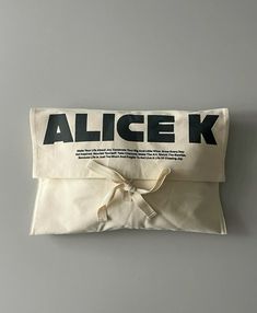 an alice k bag with a bow on the front and back side, sitting on a gray surface