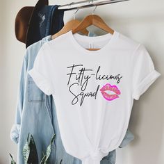 two t - shirts hanging up on a rack with clothes and plants in the background