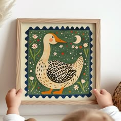 a little boy holding up a framed painting with a duck on it