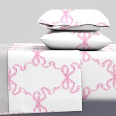 two pillows are stacked on top of each other with pink ribbon designs in the middle