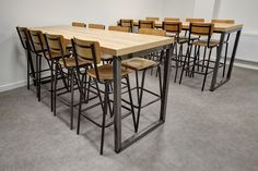 an empty room with many chairs and barstools on the floor in front of a long table