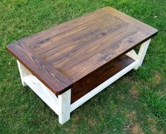 a wooden table sitting in the grass on top of a green field with white trim