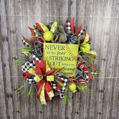 a wreath that is on the side of a wooden fence with a sign saying never let the fear of striking out