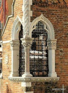 an old brick building with a wrought iron window