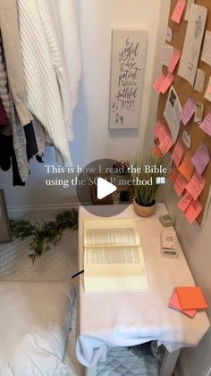 there is a small desk with a book on it and notes attached to the wall