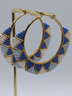 two pairs of blue and white seed beaded hoop earrings on a gold plated stand