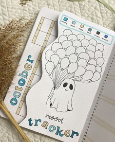 a notebook with an image of a ghost holding balloons on it next to a plant