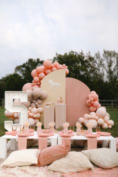 a table set up with balloons, pillows and other items for a baby's first birthday party