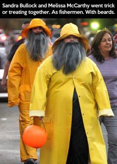 two men in yellow raincoats and hats walking down the street with an orange ball