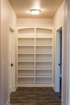 an empty walk - in closet with white shelving and wood flooring is shown