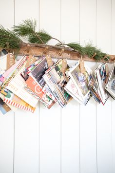 a bunch of cards are hanging on a wooden branch with twine and paper tags