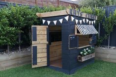 a small black and white dog house in the grass with flags on it's roof