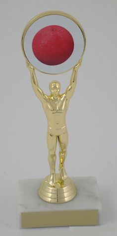 a gold trophy with a red ball in the center and a man holding it up